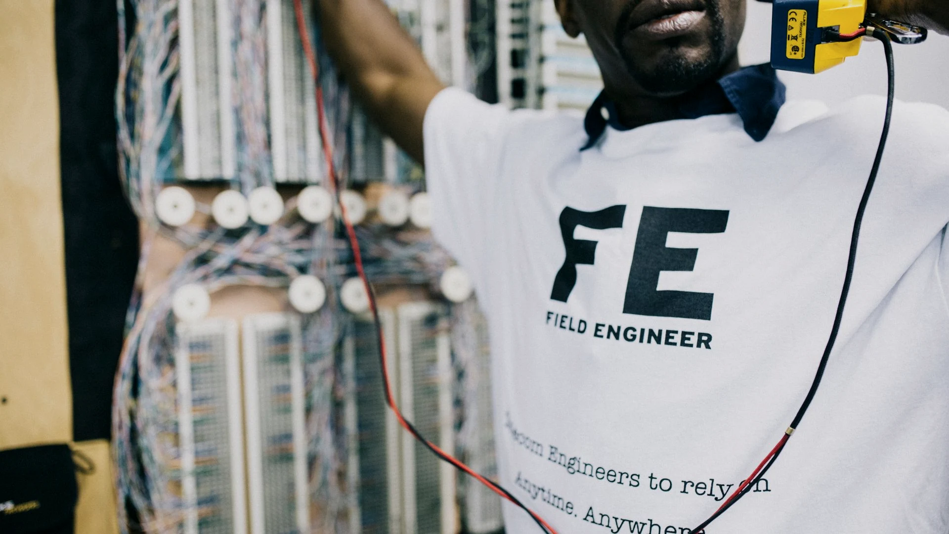 Field engineer servicing database server rack wiring during a production data migration cutover